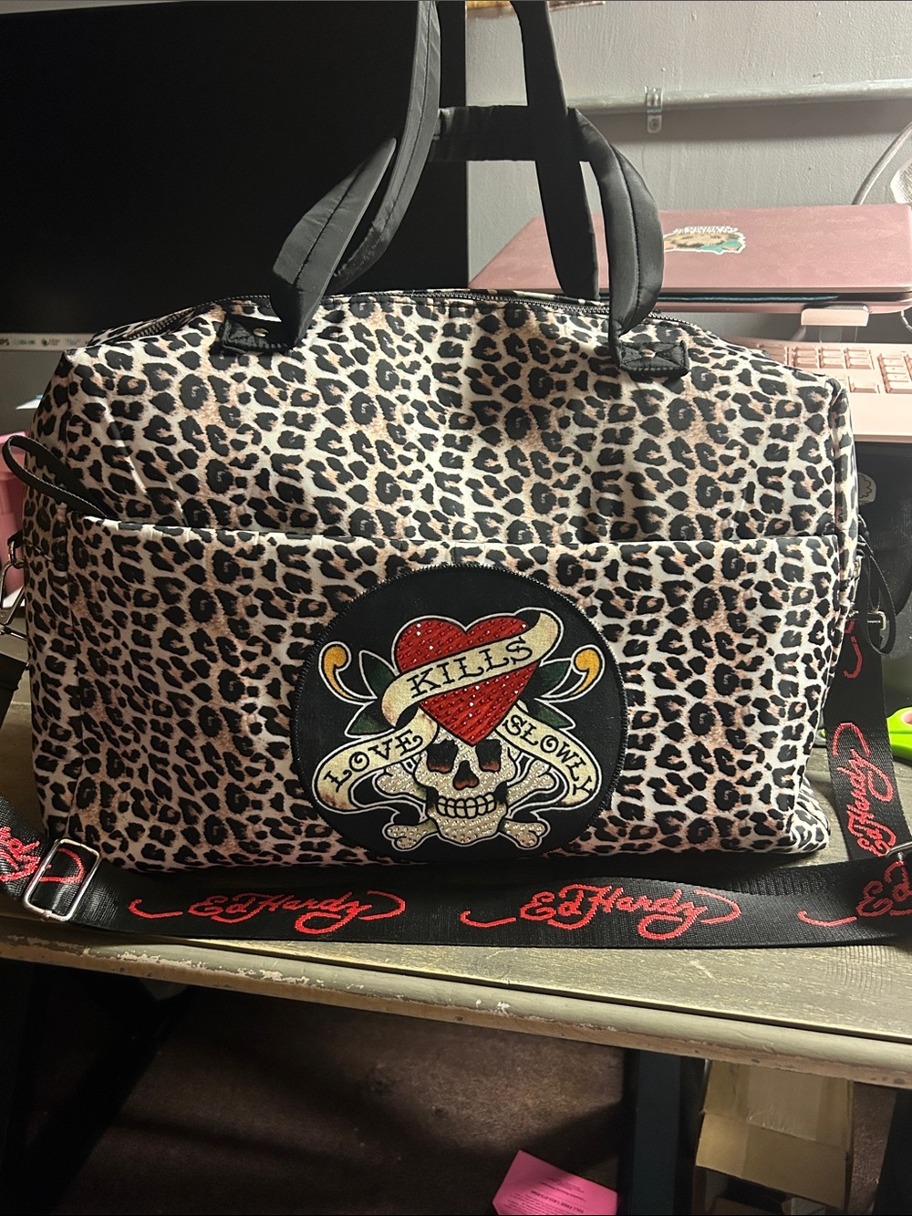 Ed Hardy leopard print duffel travel bag features a "Love Kills Slowly" skull